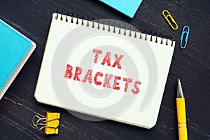 Business concept about TAX BRACKETS with sign on the page. Tax bracketsÂ show you theÂ taxÂ rate you will pay on each portion of